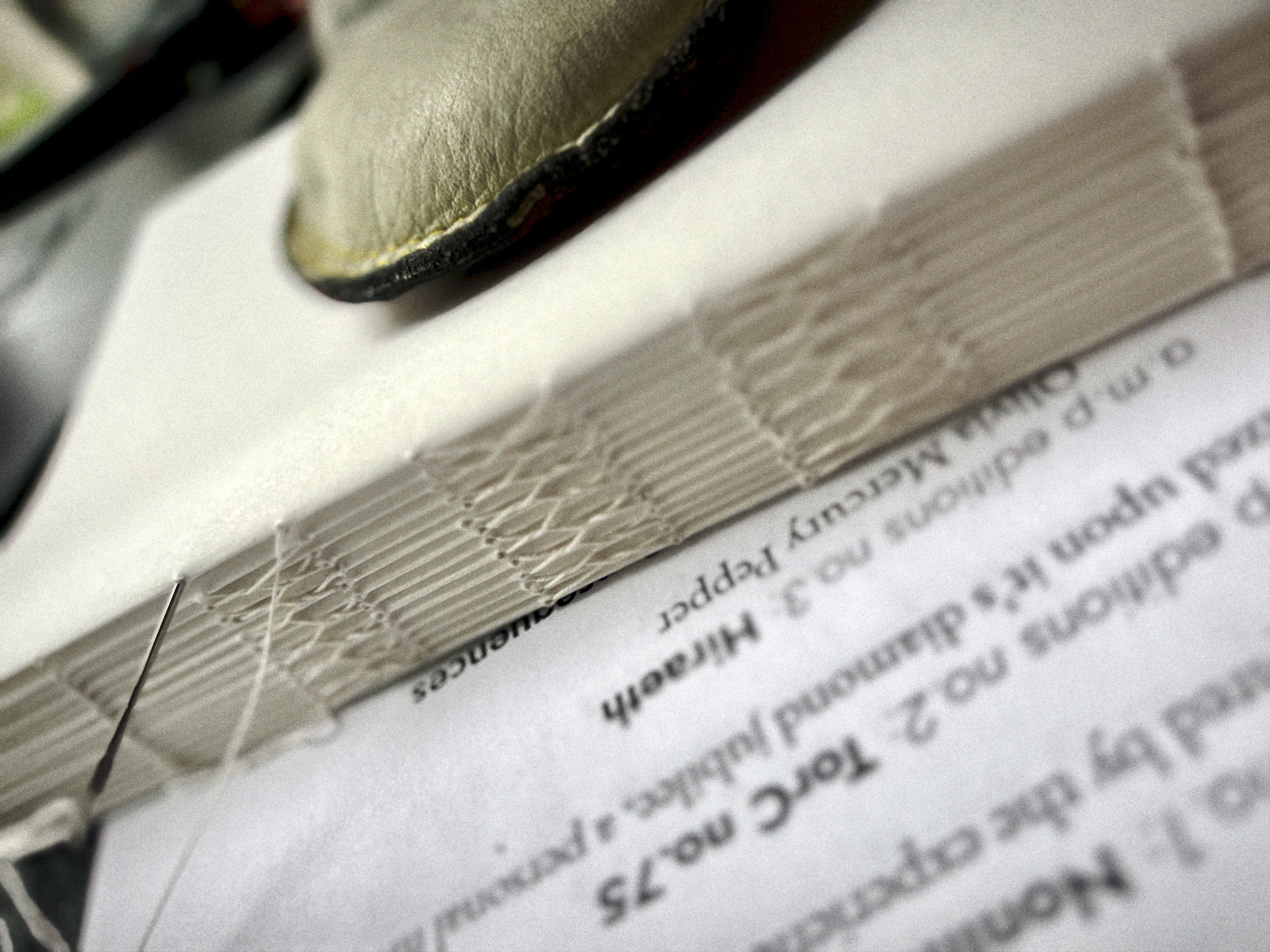 A close up photo of the spine of a text block being sewn in french stitch sewing technique